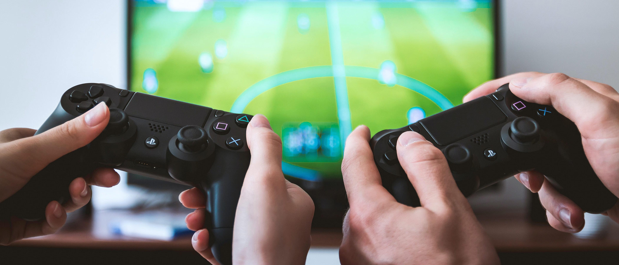 Hands of two people side by side using controllers for gaming