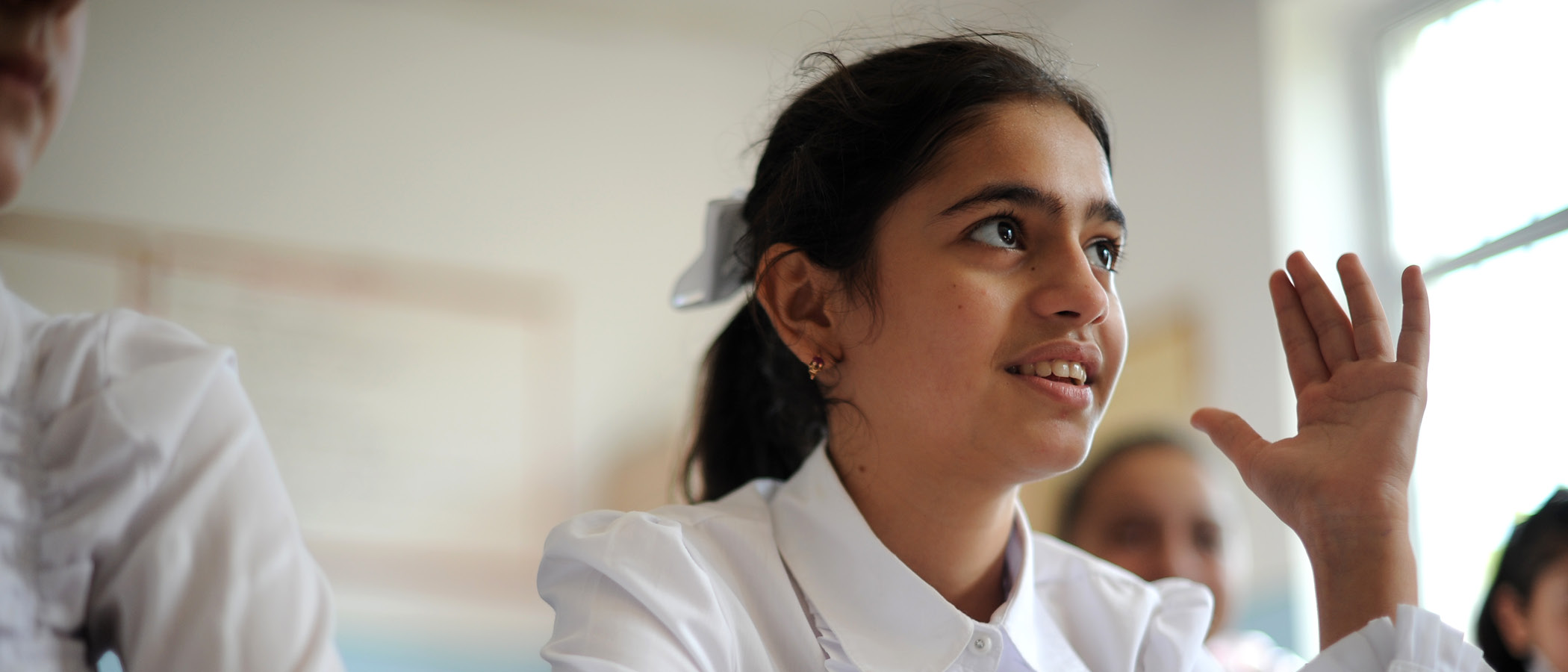 Student raising her hand in classroom
